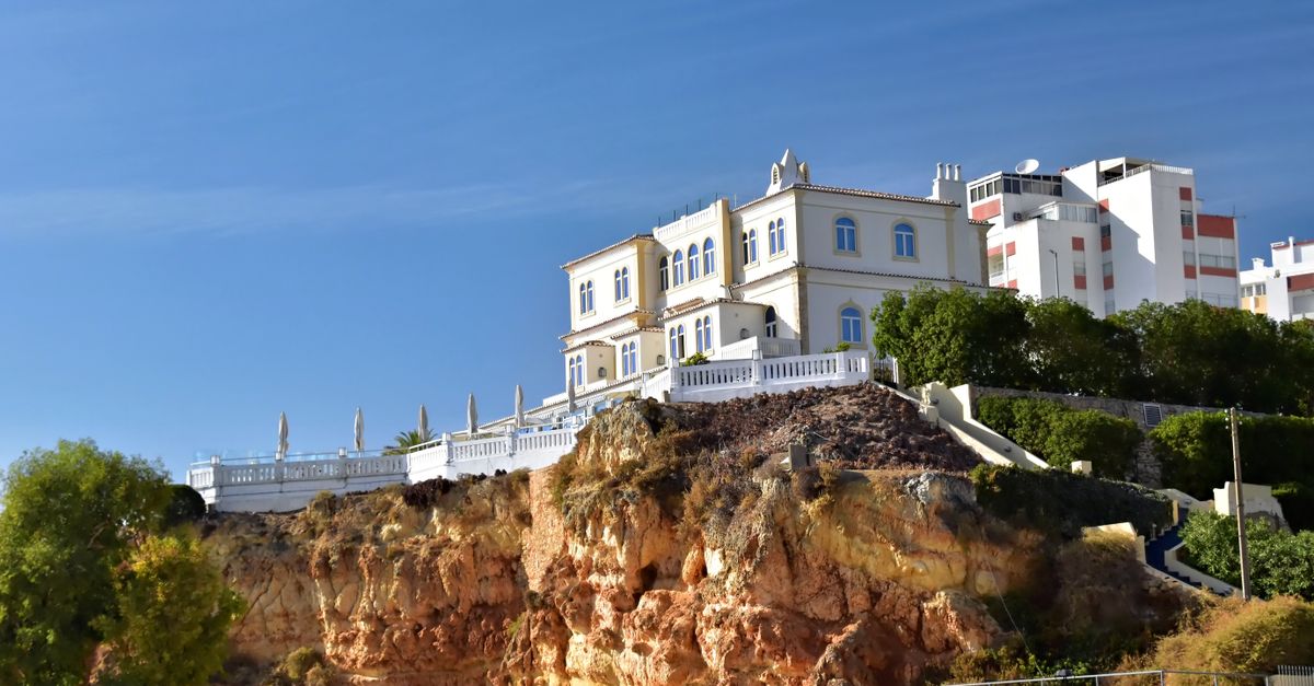 Elegant villa on a rocky Algarve cliff with clear blue skies in Faro District, Portugal.