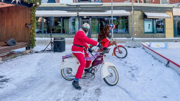 Two Santa Clauses on vintage scooters enjoy a snowy day in Boden, Sweden.