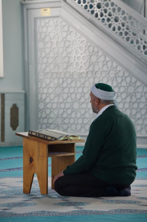 Free An elderly man in prayer inside a beautifully decorated Islamic mosque, focusing on spirituality. Stock Photo
