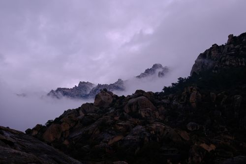Free A dramatic view of rocky mountains shrouded in mist at twilight with a mystical ambiance. Stock Photo