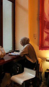 A woman in a coffee shop gazing out the window, enjoying a peaceful moment with a cup of coffee.
