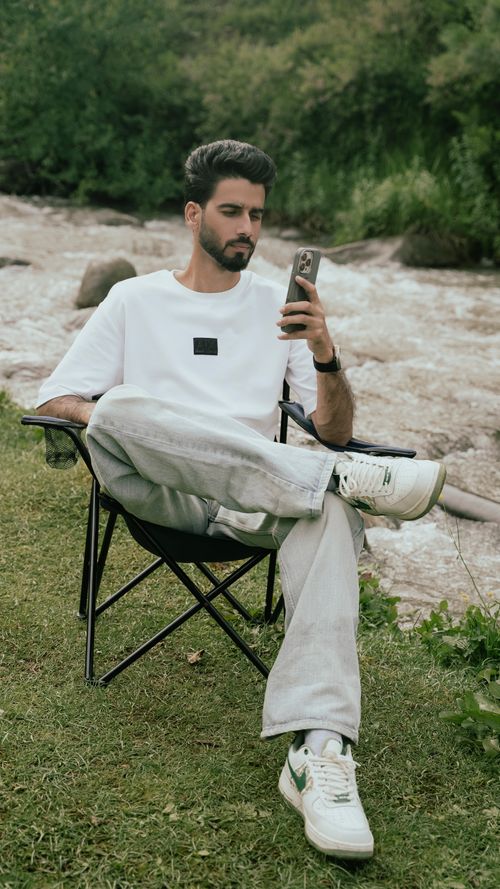 Free A young man sits comfortably by a scenic river in an Indian forest, enjoying the serene environment. Stock Photo
