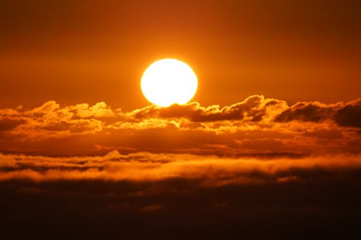 Breathtaking sunset over clouds in Ireland, capturing vibrant orange hues and the sun's glow.