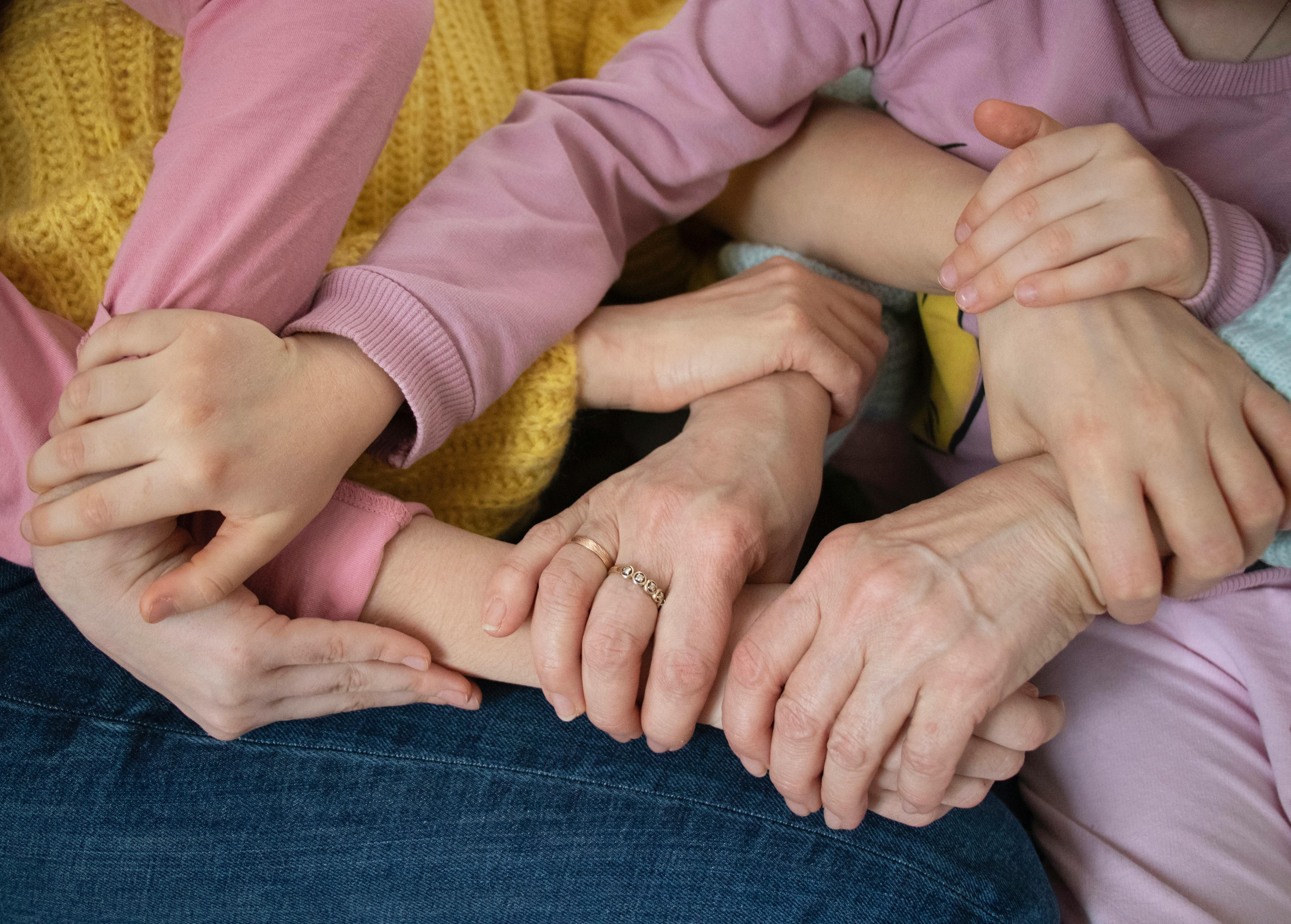 Multiple arms intertwined, symbolizing family unity and support across generations.