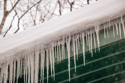 Free Winter scene of icicles hanging from a rooftop after heavy snowfall. Stock Photo