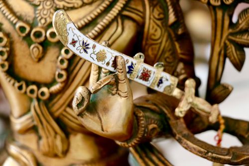 Free Intricate brass statue hand holding a decorated sword, showcasing Indian craftsmanship. Stock Photo
