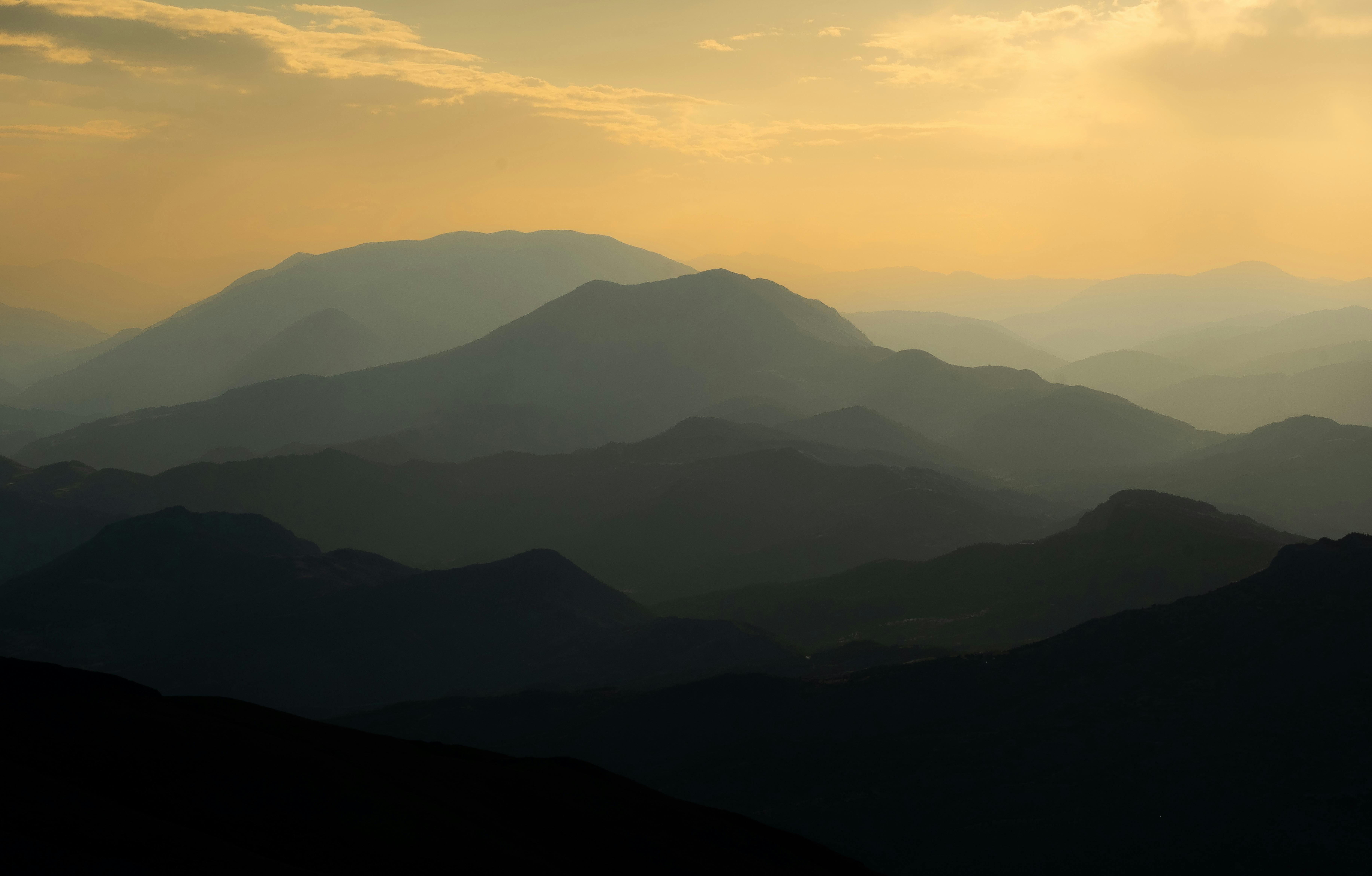 Gratuit Silhouette paisible d'une montagne à l'aube, baignée d'une douce lumière dorée. Photos