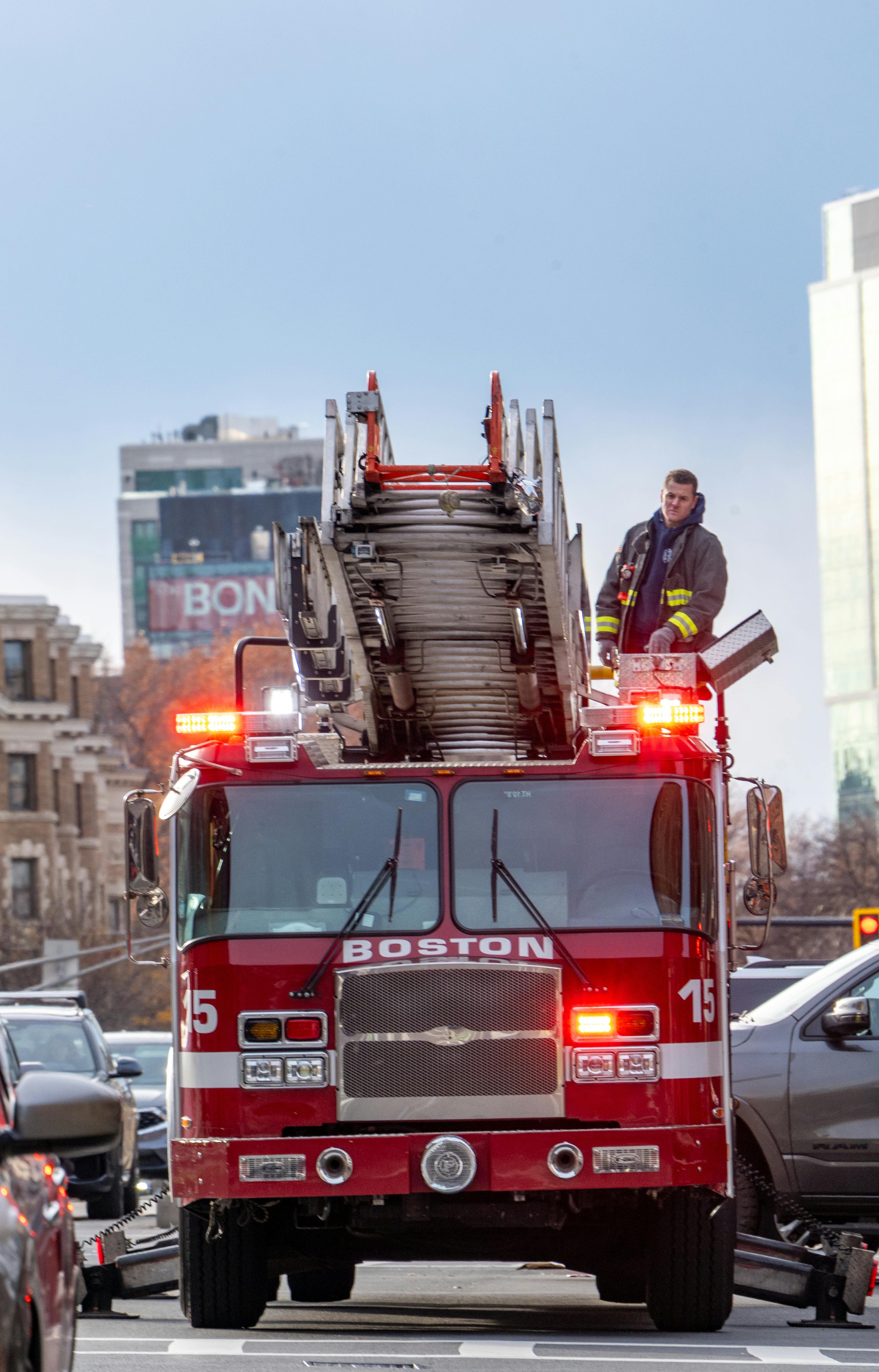 Free A Boston firetruck with extended ladder and firefighter in action on a city street. Stock Photo