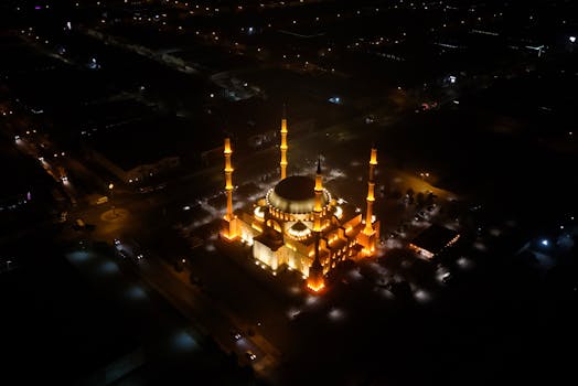 A stunning aerial shot of an illuminated mosque at night.