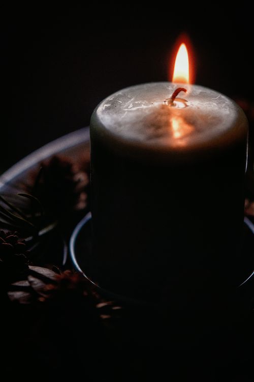 Free Moody candle flame illuminating a dark setting with warm tones. Stock Photo