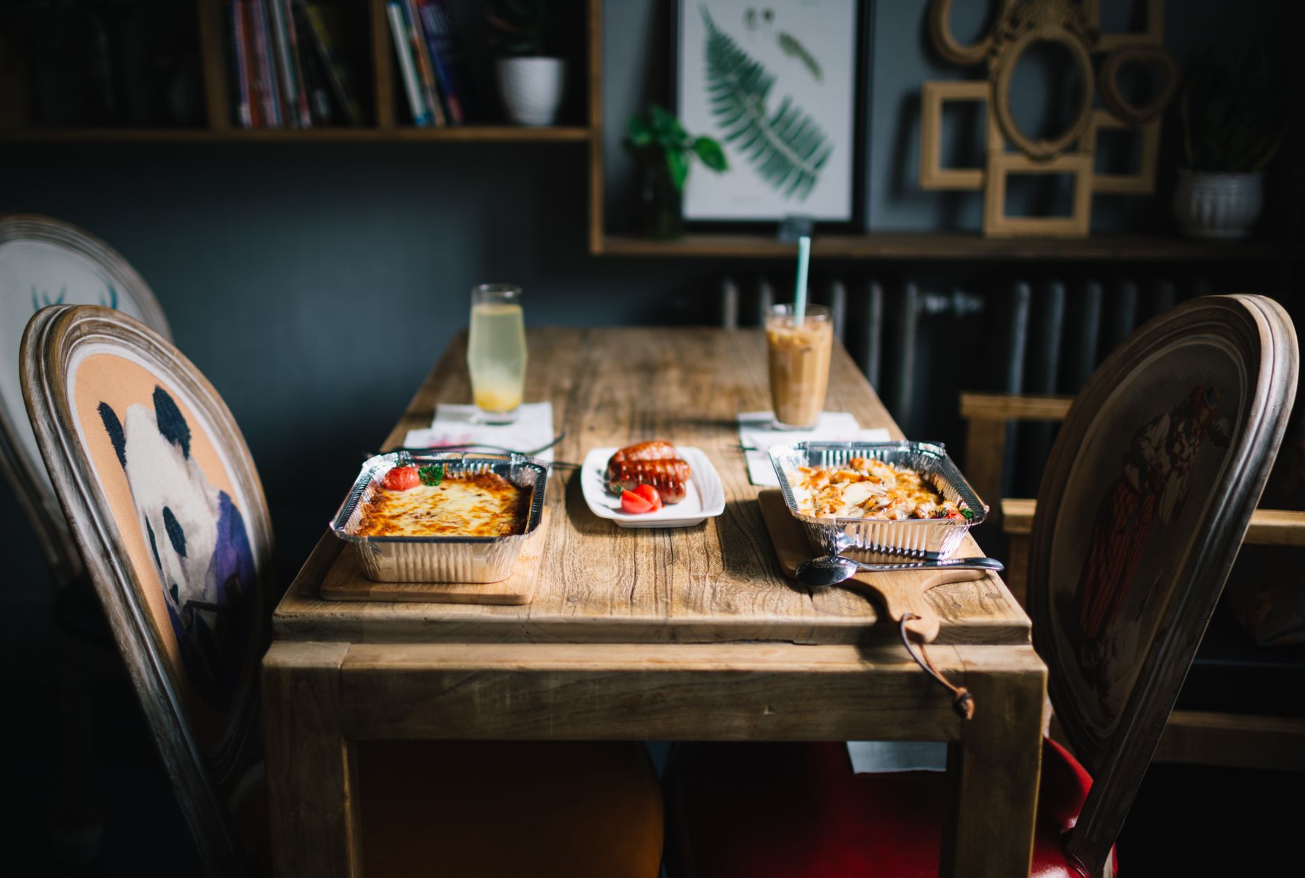 A rustic dining setup with served meals and beverages on a wooden table in a cozy indoor setting.