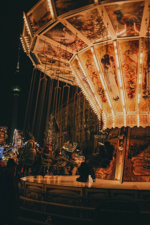 Free Illuminated carousel at a Berlin Christmas market at night, surrounded by holiday lights. Stock Photo