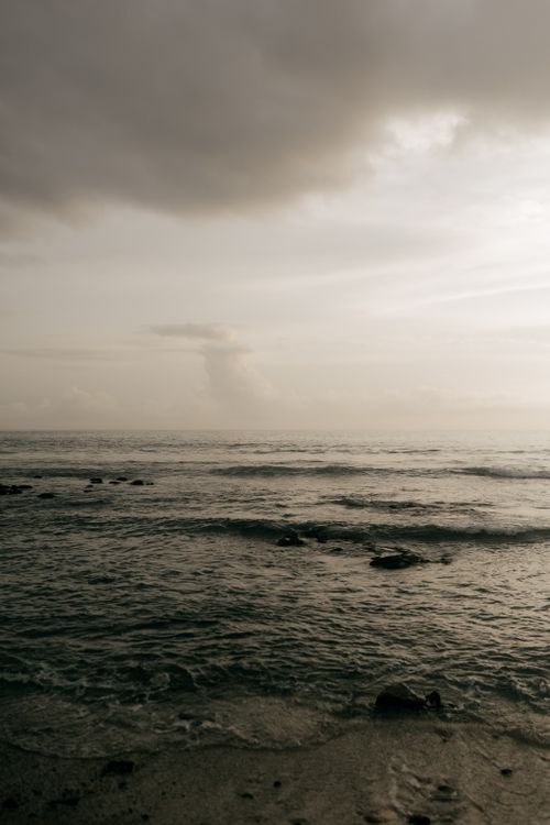 Free Serene ocean view at dusk with calming waves and a dramatic cloudy sky. Stock Photo