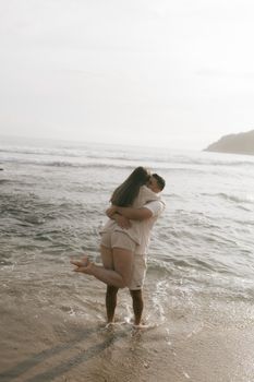Couple sharing a tender moment on a sandy beach at sunset, creating a romantic atmosphere.