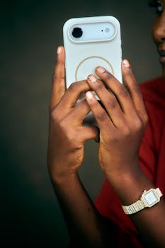 Close-up of hands holding a smartphone, showcasing a stylish watch.
