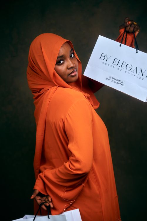 Free Confident woman in orange hijab with stylish shopping bags in hand. Stock Photo