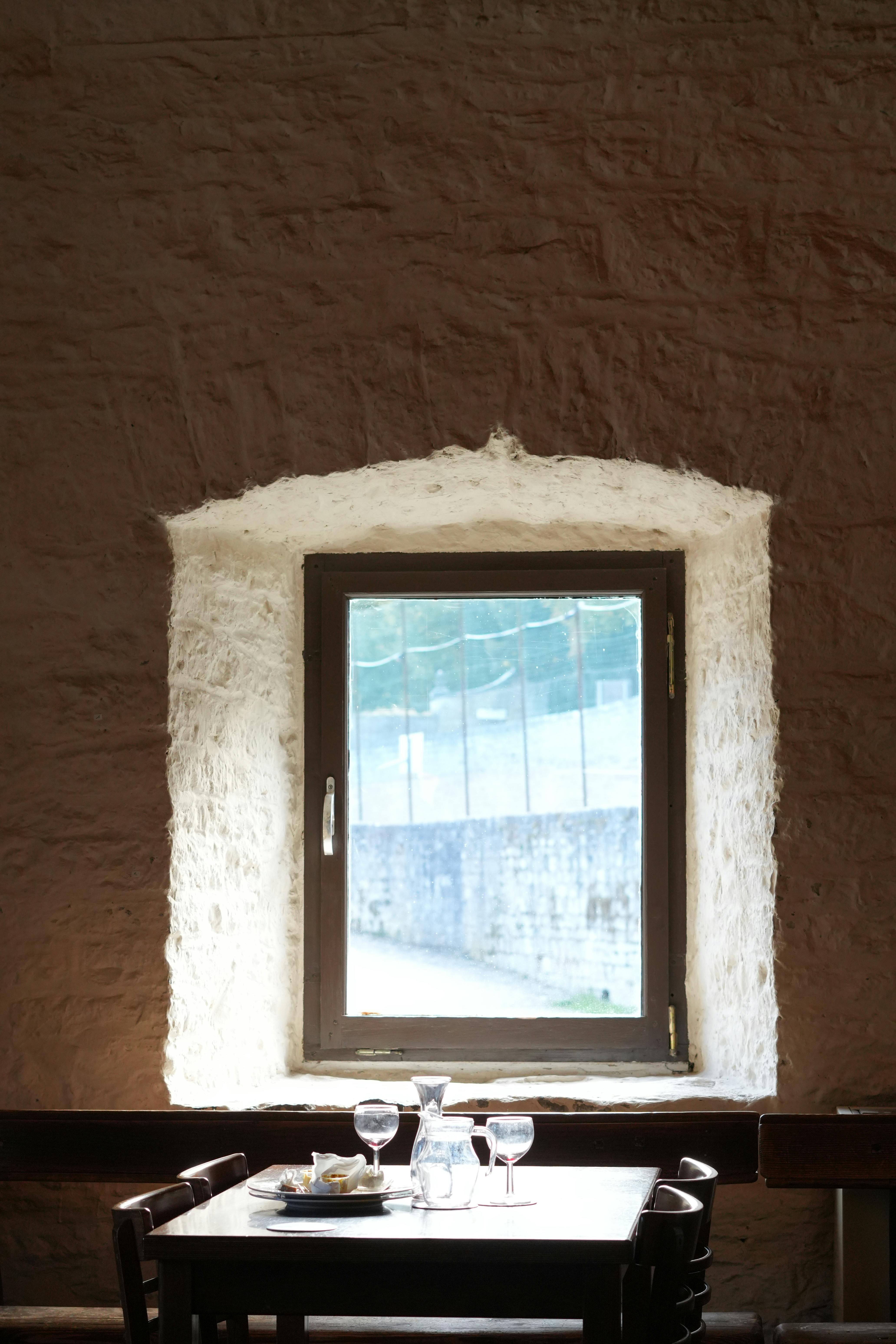 grátis Uma mesa de jantar pitoresca e uma janela ensolarada criam uma atmosfera serena em Floreffe, na Bélgica. Foto profissional