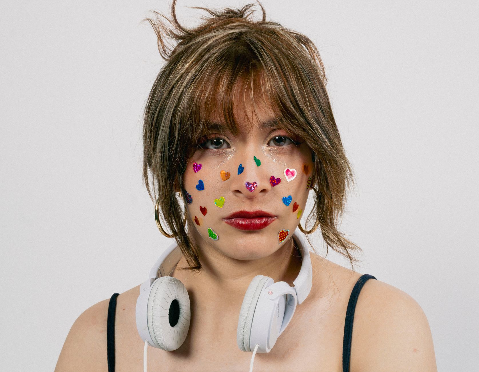 A young woman with colorful face stickers and headphones, representing youthful style and creativity.