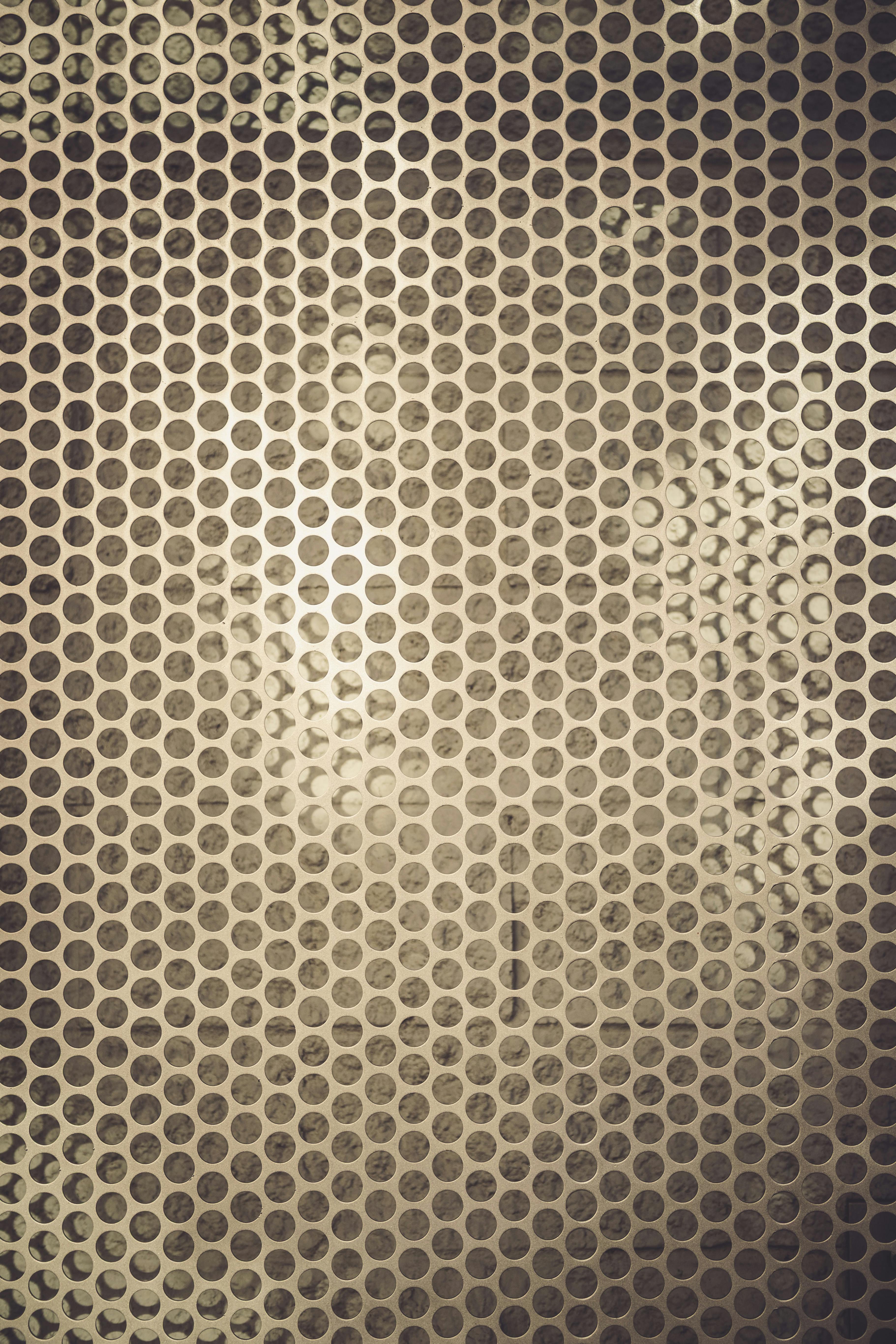 Free Artistic abstract image of a metallic perforated surface with a circular pattern and soft gradient lighting. Stock Photo