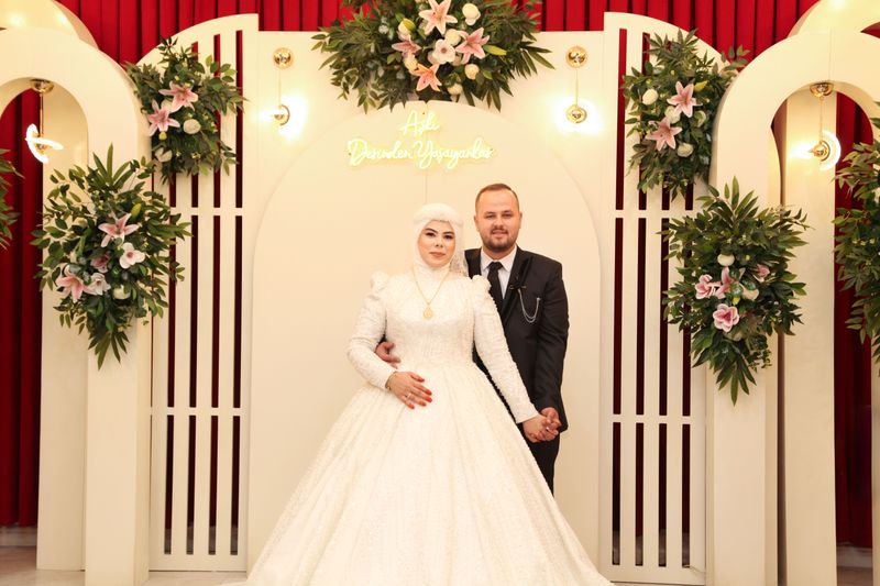 Beautiful couple in elegant wedding attire surrounded by floral decor indoors.