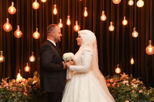 Free Bride and groom sharing a romantic moment with warm lighting and floral decorations. Stock Photo