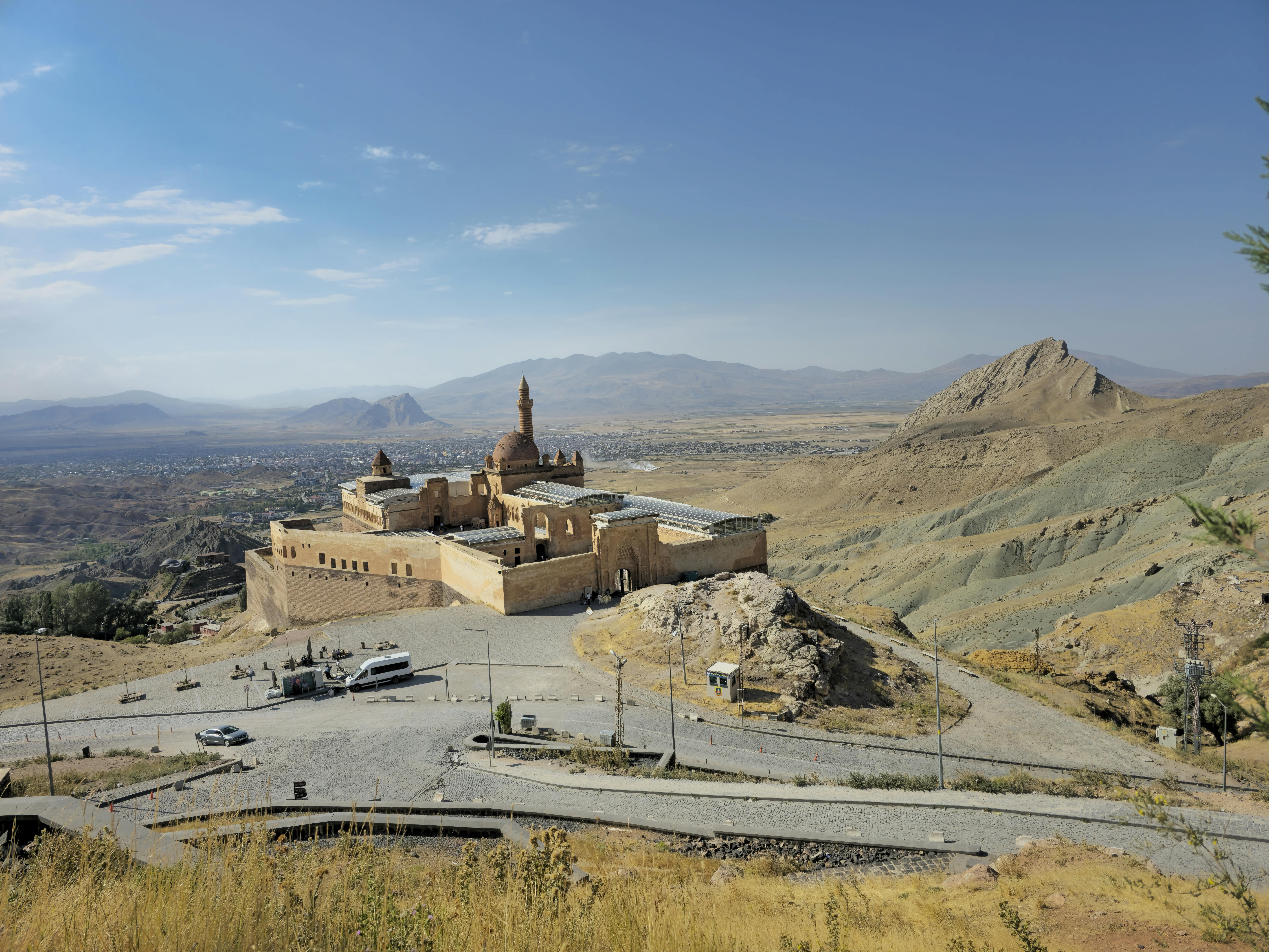 Scenic view of historic Ishak Pasha Palace amidst beautiful Ağrı landscape under clear skies.