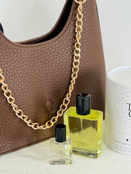 Chic brown handbag paired with luxury perfume bottles, perfect for style enthusiasts.