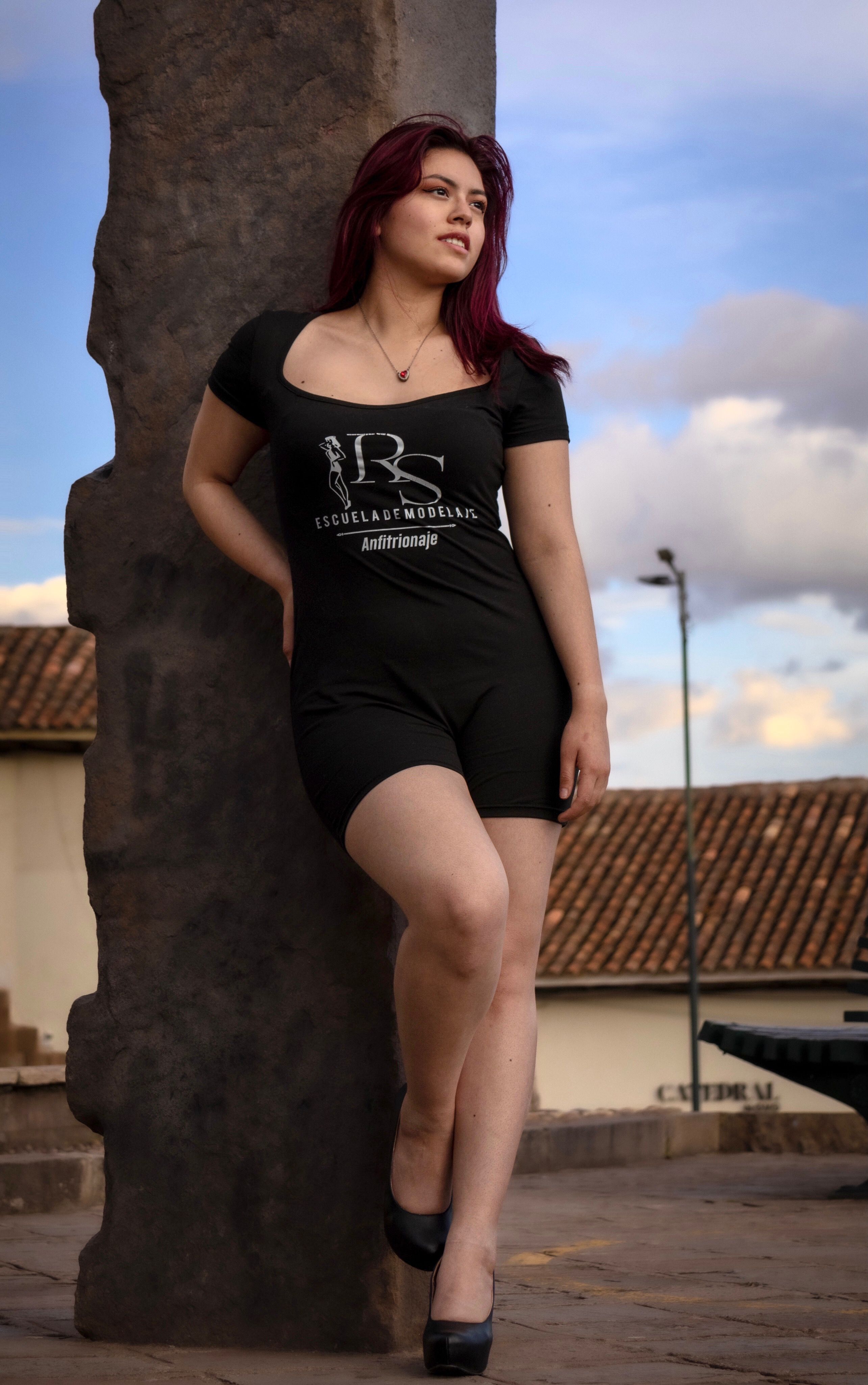 Young woman posing near ancient stone in Cusco, Peru. Stylish urban fashion image.