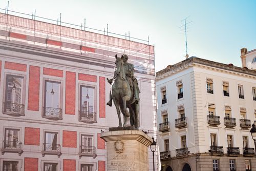 Free Equestrian statue of Carlos III in a Madrid plaza with architectural backdrop. Stock Photo