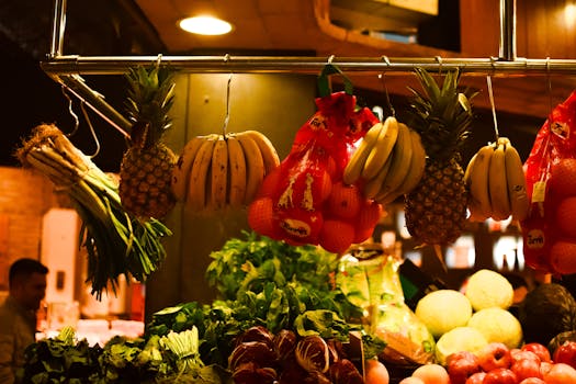 Colorful assortment of fresh fruits and vegetables hanging at an indoor market stall.