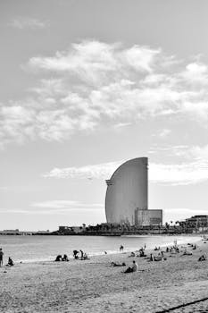 Black and white image of Barcelona beach with W Hotel and scattered people enjoying the day.