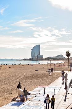 A vibrant scene of Barceloneta Beach with people enjoying the sunny weather in Barcelona.