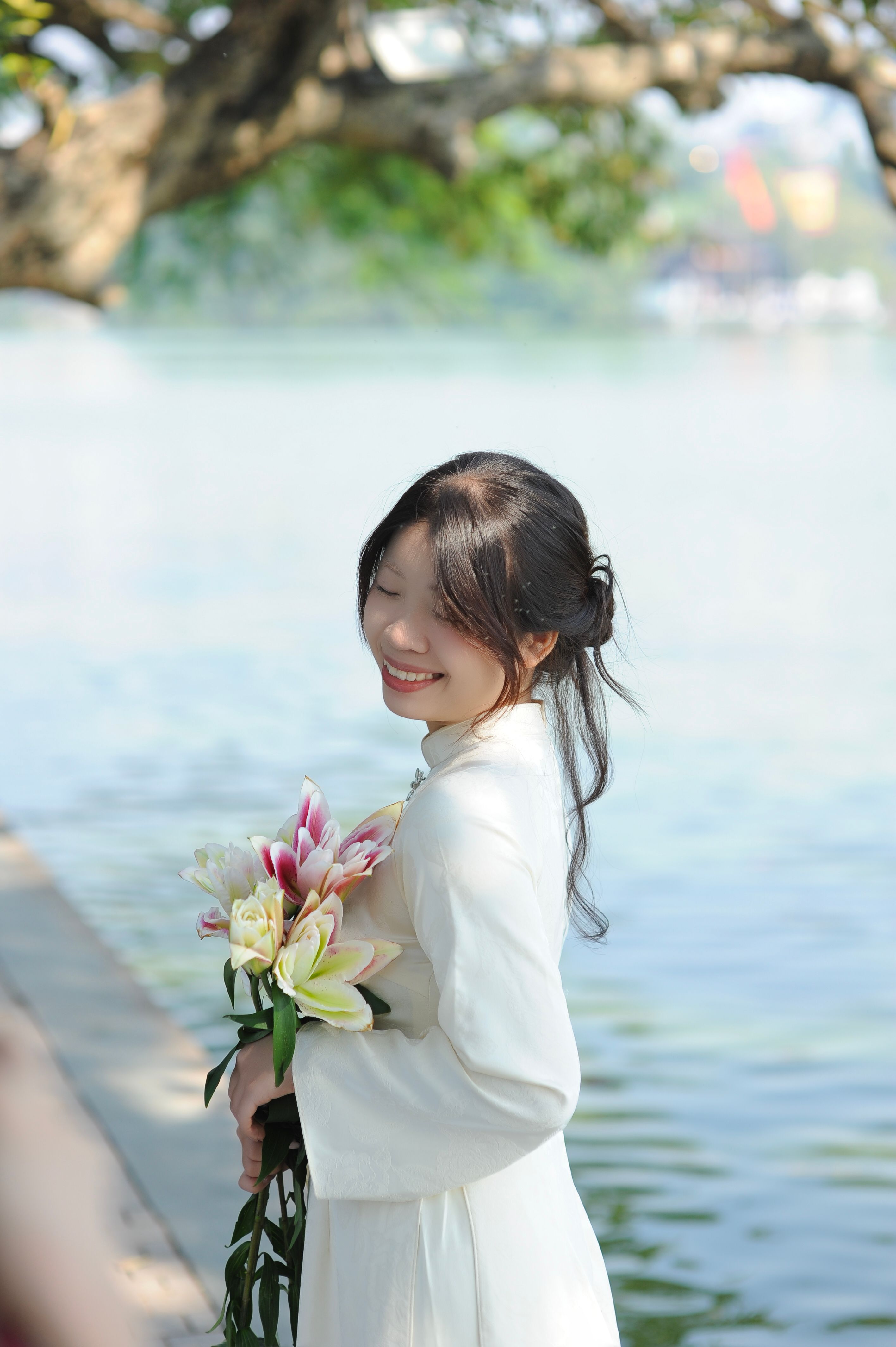 Woman in White Dress Holding Flowers by the Lake · Free Stock Photo