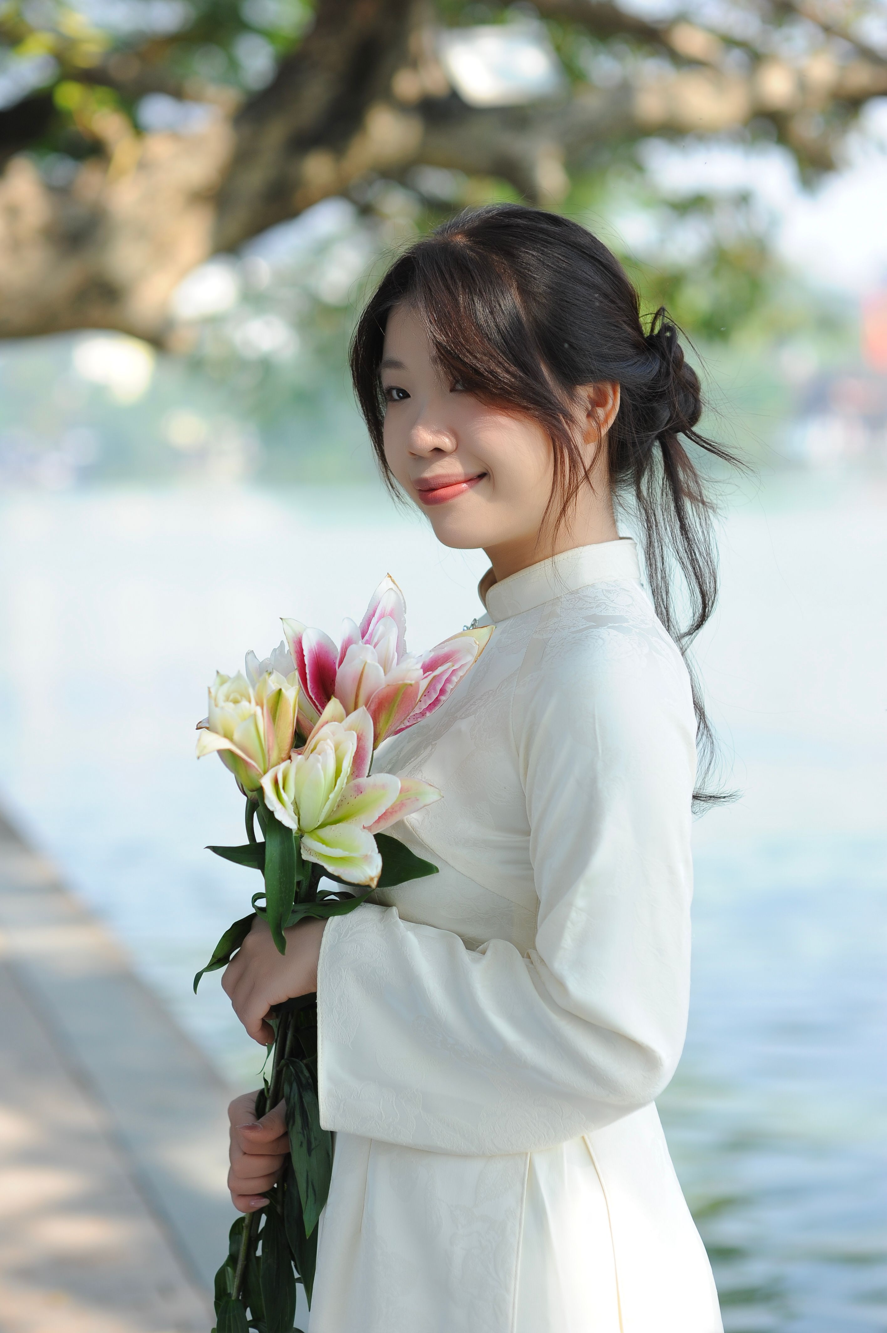Young Woman in Traditional Dress Holding Lilies Outdoors · Free Stock Photo