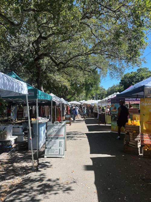 Free Sunny day at a bustling outdoor market with vendor tents and shoppers. Stock Photo