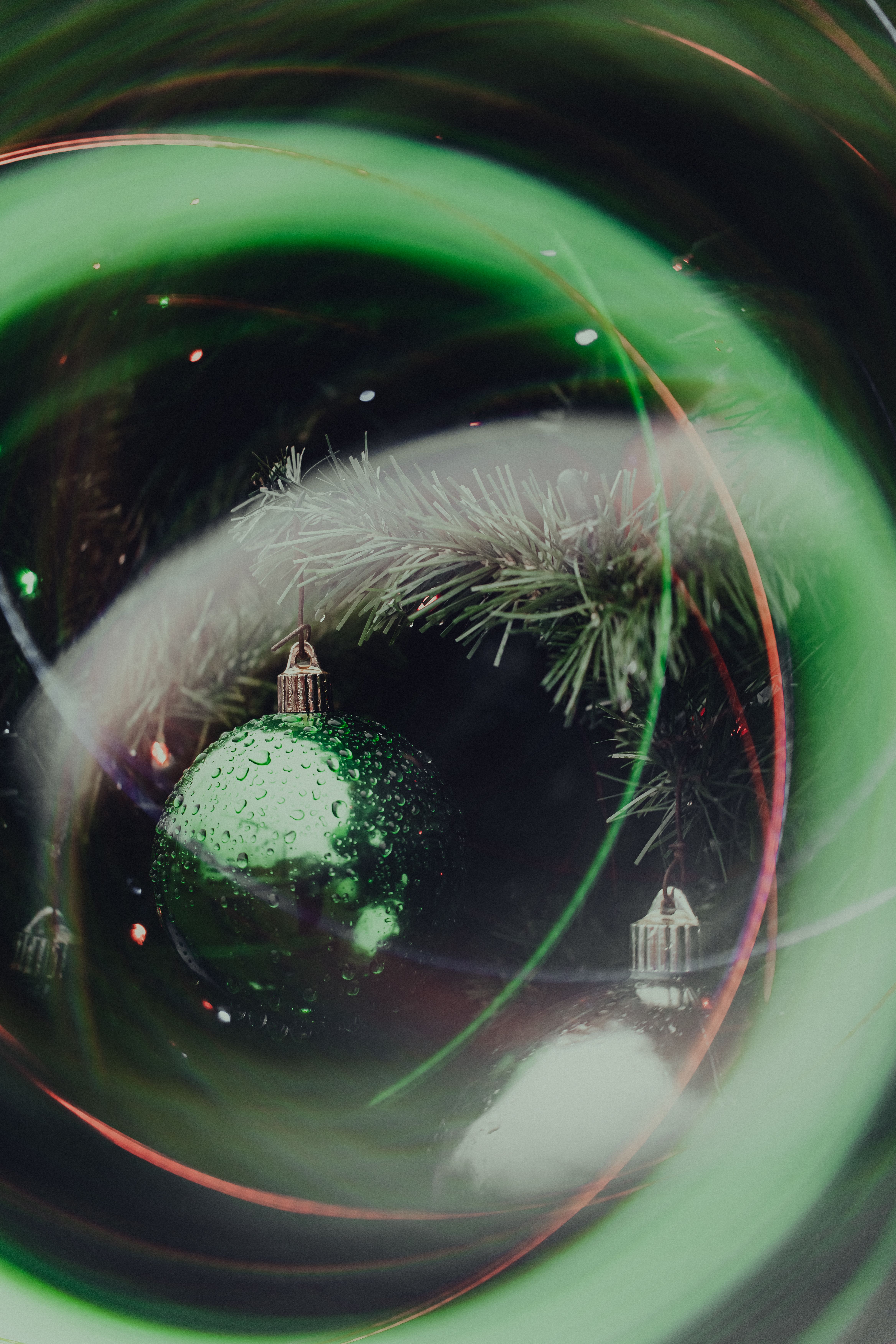 Close-up of a green Christmas ornament with artistic reflections and lights.