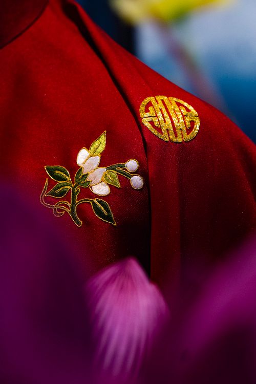 Free Close-up of red fabric with intricate floral embroidery and gold Chinese symbols. Stock Photo