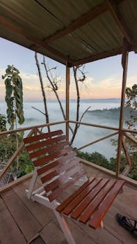 Relaxing mountain cabin with a scenic view over misty hills at sunrise.
