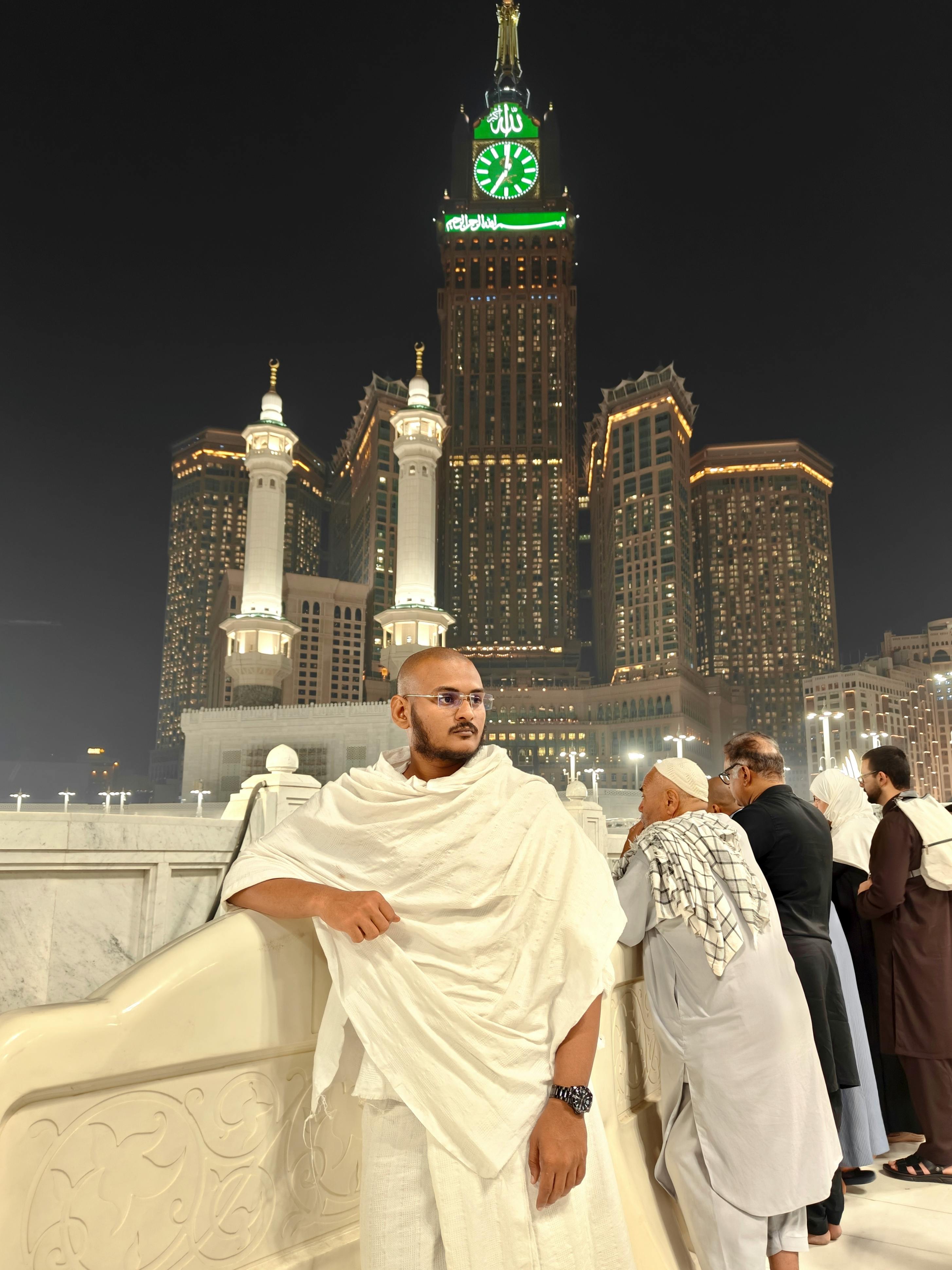 Pilgrims gather at night in front of Abraj Al Bait Towers, Mecca's iconic skyscraper, during Hajj.