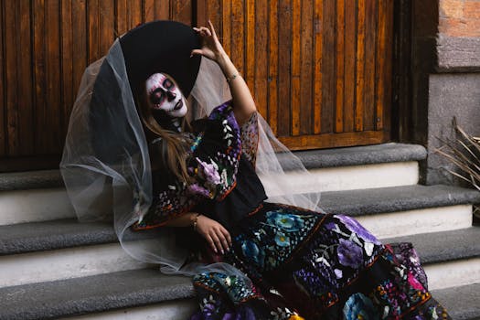 A woman in traditional Day of the Dead attire with face paint, sitting outdoors in Toluca, Mexico.