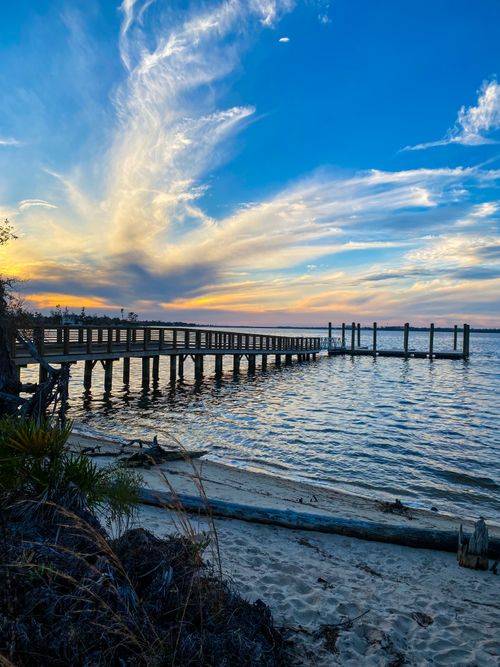 Free Peaceful sunset view over a wooden pier and calm ocean waters. Stock Photo
