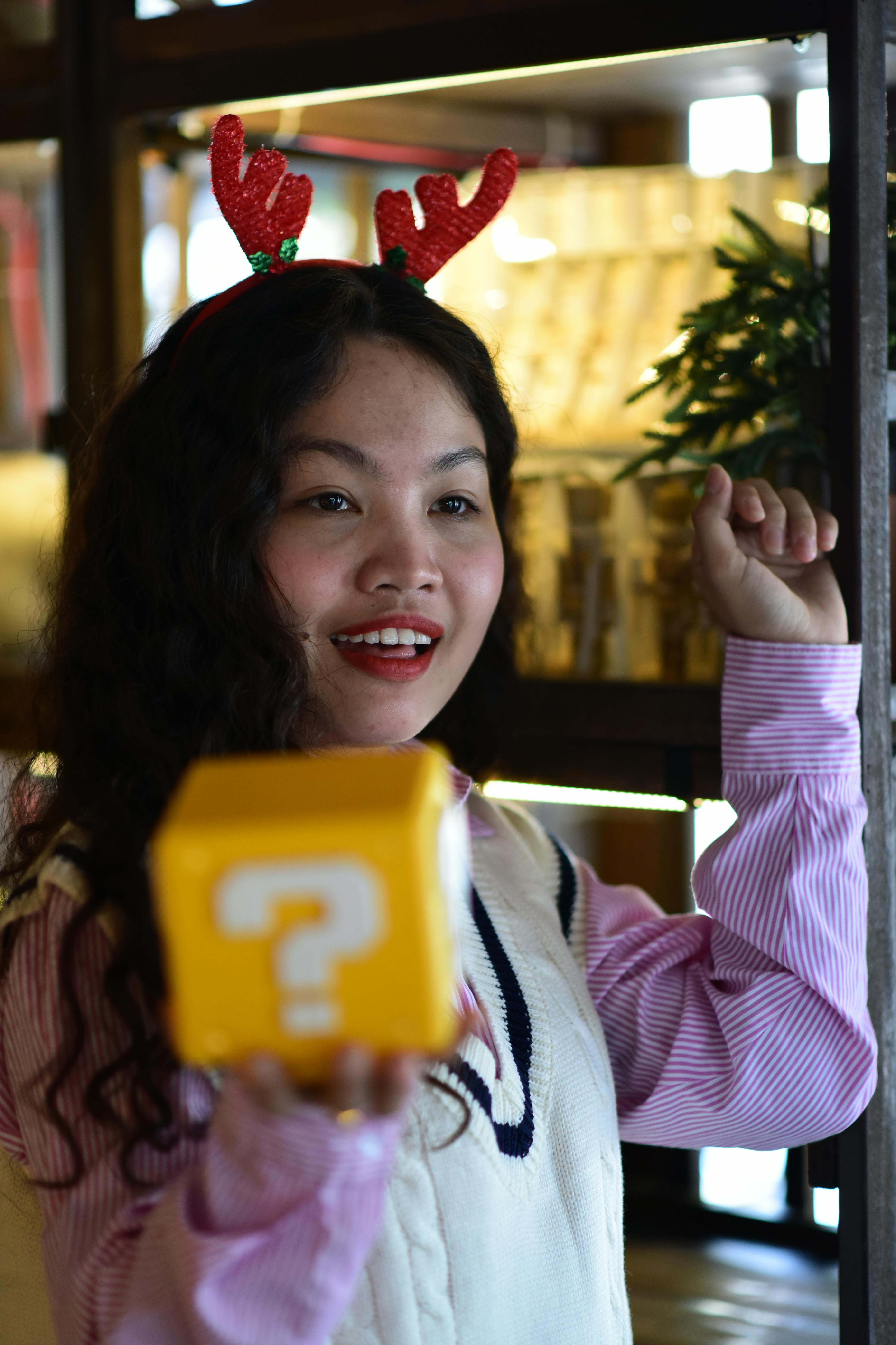 De franc Una dona alegre amb banyes festives sosté un bloc de preguntes a l'interior, capturant l'esperit nadalenc. Foto d'estoc