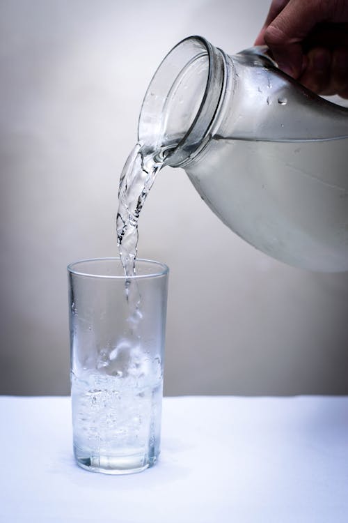 бесплатная Прозрачный стеклянный кувшин, наливая воду на прозрачный стакан для питья Стоковое фото