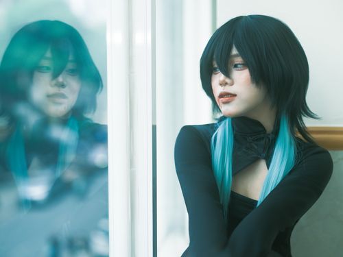 Free Young woman with blue hair highlights gazing out a window, reflecting introspective mood. Stock Photo