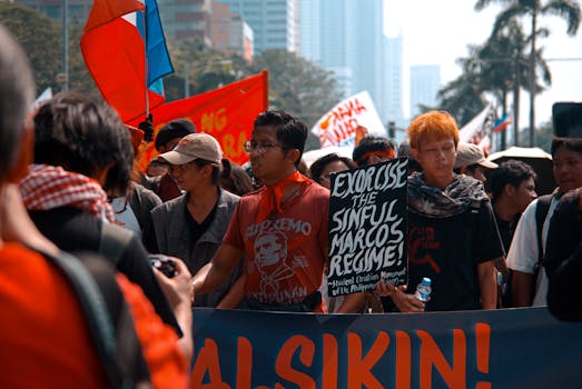 Group of protesters marching with signs and flags in an urban setting, advocating for political change.