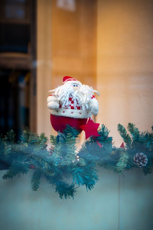 Free A charming Santa Claus ornament in a holiday window display with evergreen garland. Stock Photo