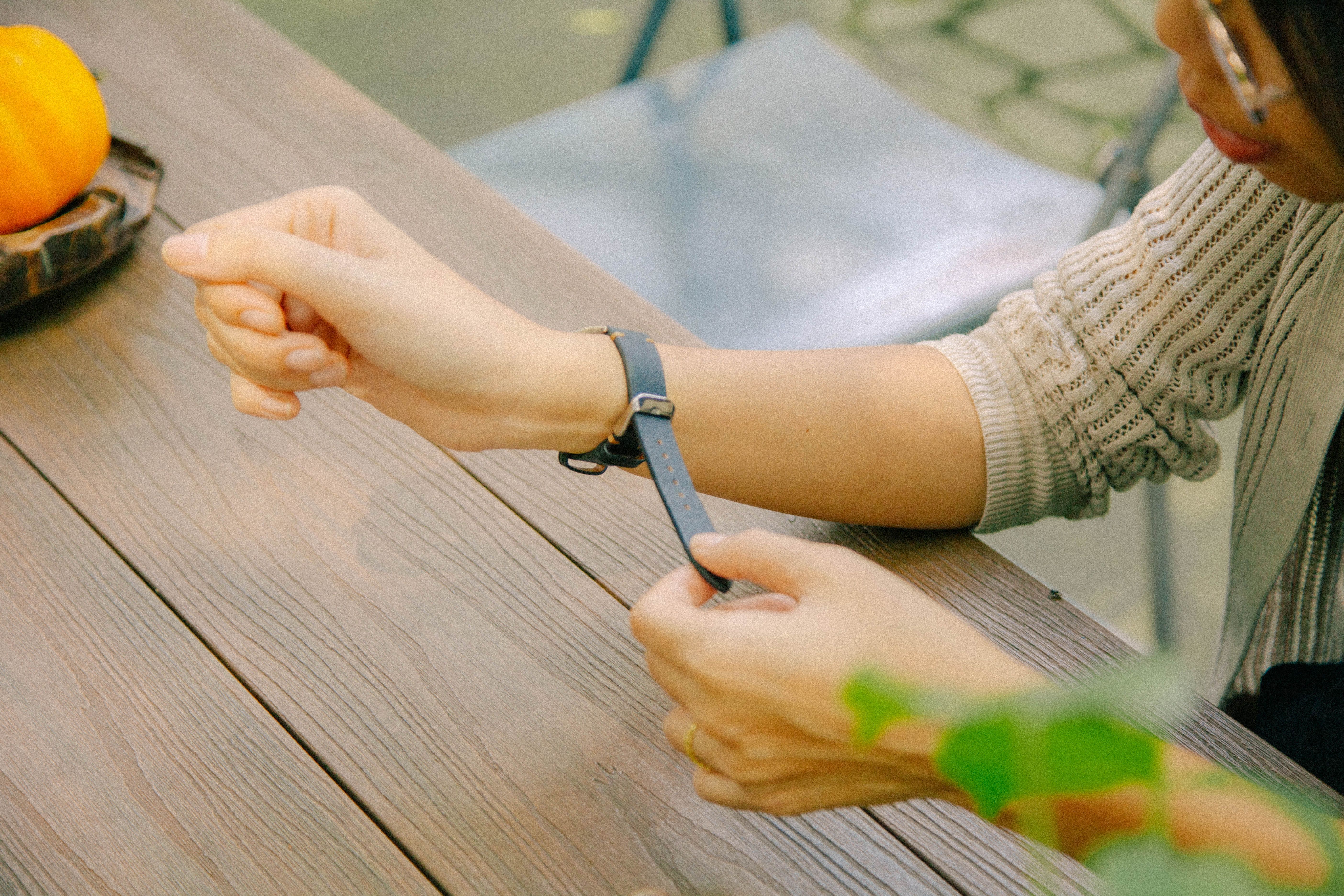 Close-up of a person adjusting a wristwatch at an outdoor cafe table, adding a casual feel.