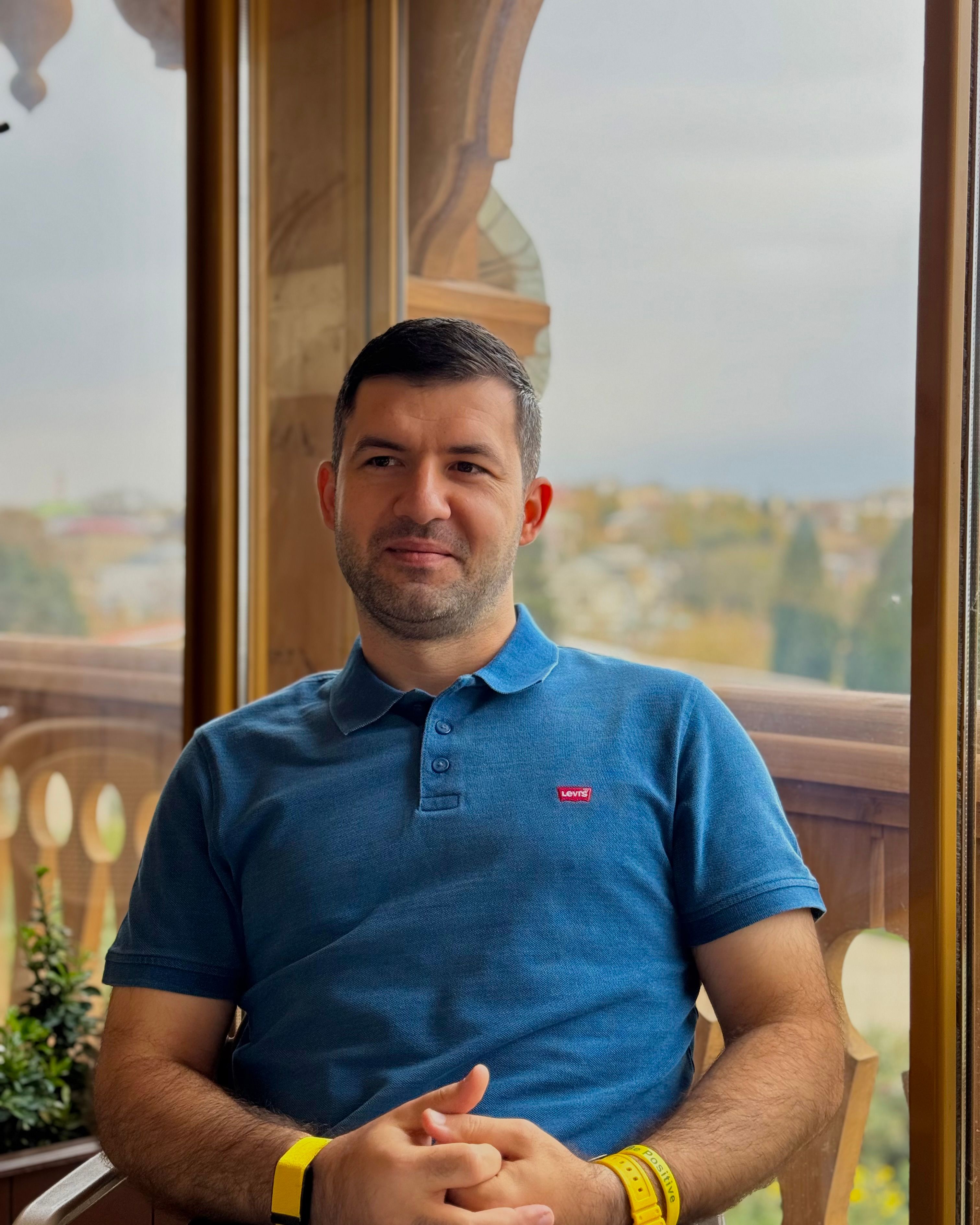 A man seated in a cafe with a scenic outdoor view, enjoying a peaceful moment.