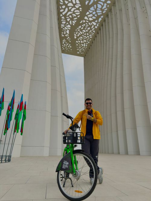 Free A person with a bicycle stands near a distinctive architectural feature in Baku, Azerbaijan. Stock Photo