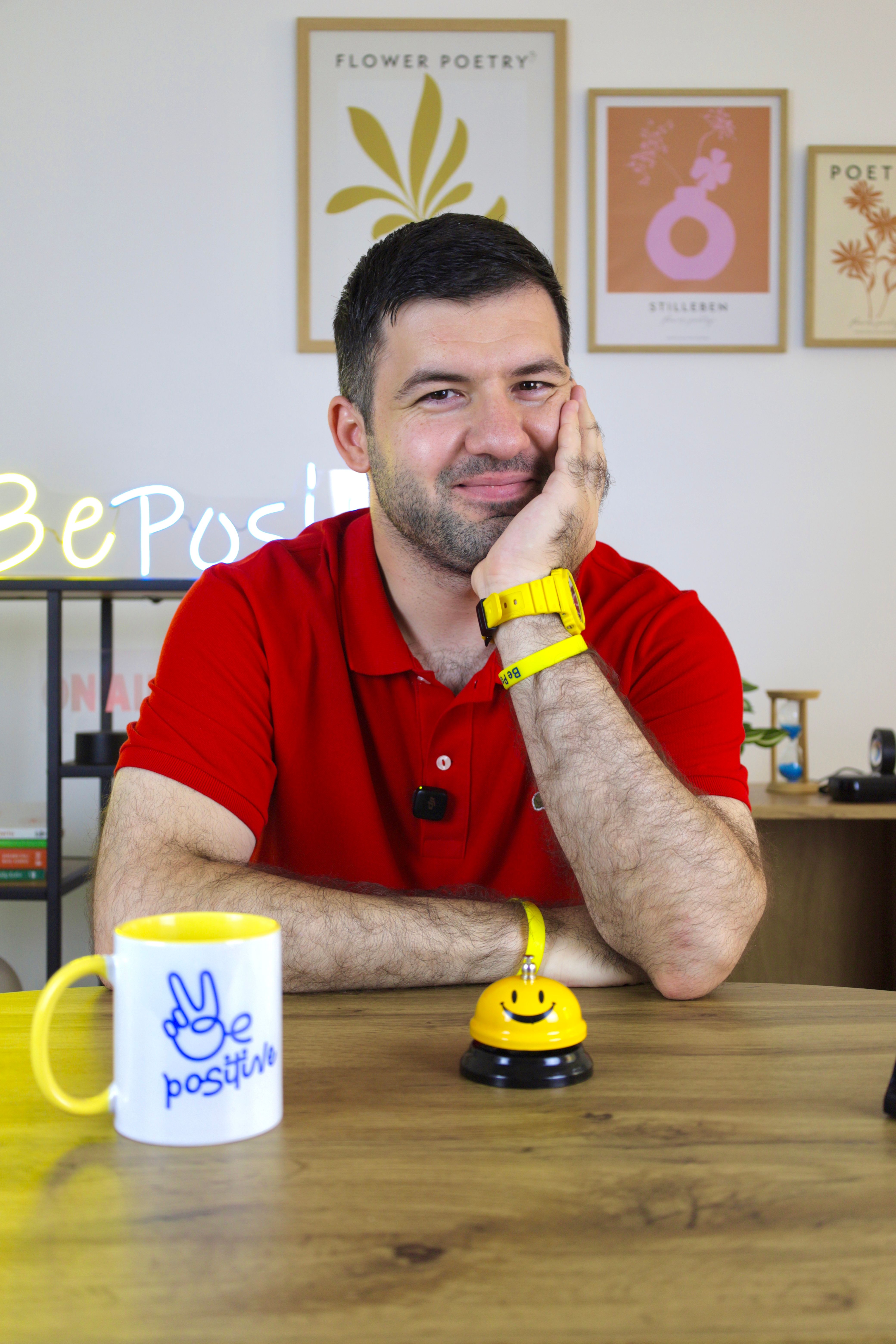 Man smiling at a desk with motivational decor and a 'Be Positive' theme.